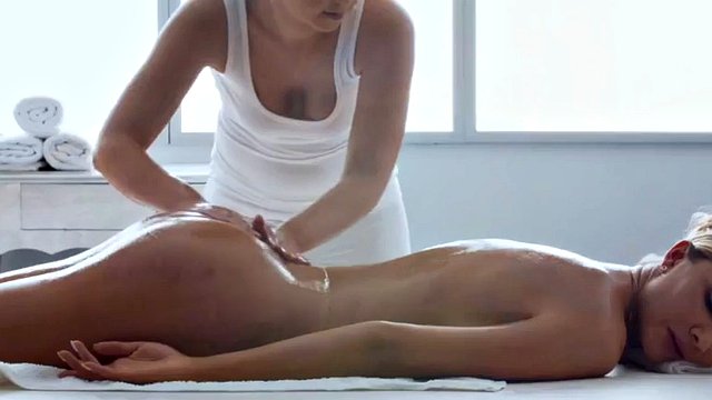 Lesbian oiled babe fingers girlfriend's pussy on massage table