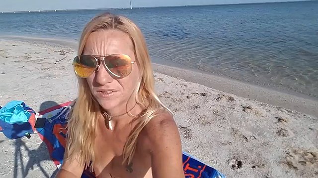 Rubia madura desnuda bronceándose en la playa